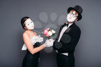 Pantomime actor and actress performing with flower bouquet. Mime theater performers posing. Comedy artists