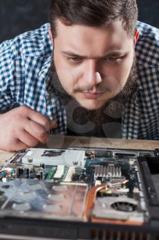 Male service engineer disassembling laptop with screwdriver. Electronic devices repairing technology