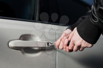 Male thief hands trying to open car door with screwdriver. Carjacker unlock vehicle. Carjacking danger