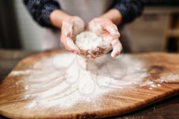Female person hands holds dough in the flour over the cutting board. Cake cooking