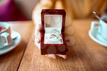 Female person hand holds box with golden wedding ring closeup view
