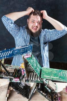 Repairman builds house of cards from motherboards. Engineer makes electronic components diagnostic. Broken computer hardware