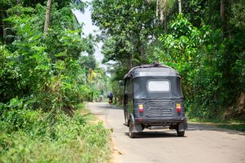 Tuk tuk on road of Sri Lanka, back view. Ceylon tropical forest and traditional tourist transport