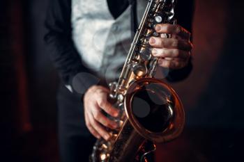 Jazz man hands holding saxophone closeup. Brass band musical instrument. Solo jazz-man with sax in studio