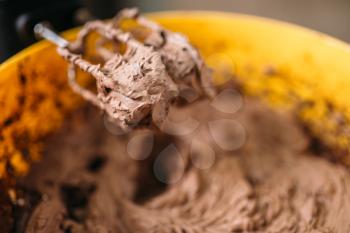Dough and chocolate powder whipped in bowl with a mixer closeup view. Sweet cake ingredients preparation