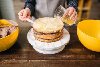 Woman cook hands pours cake with sugar syrup. Tasty dessert homemade cooking