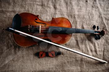 Violin, fiddlestick and bowtie on grunge canvas background, closeup view