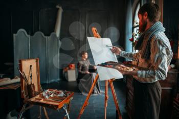 Male painter drawing portrait against female poseur in studio. Oil paint
