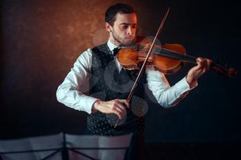 Male violinist playing classical music on violin. Fiddler man with musical instrument