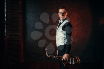 Portrait of male saxophonist with saxophone, jazz man with sax. Classical brass band instrument