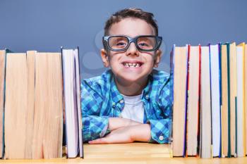 Happy pupil in glasses against books, getting elementary knowledges in school
