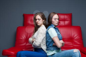 Women quarrel,two quarreling girlfriends sits on red leather couch