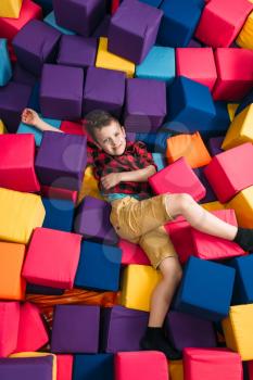 Little boy having fun with soft colorful cubes in childrens entertainment center. Happy childhood