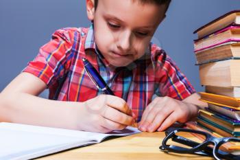 Little child writing in notebook, school homework concept. Young pupil at the desk in classroom