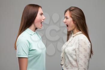 Two girls screams at each other, studio photo shoot. Women quarrel