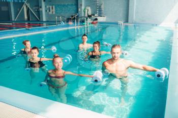 Women aqua aerobics traninig with dumbbells in indoor swimming pool. Female group with male trainer, water sport