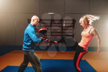 Woman in actoin on self defense workout with personal instructor, fighting training in gym, martial art