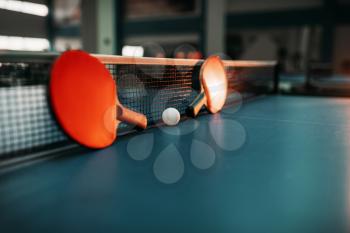 Two tennis rackets and ball against net on the table, game concept. Ping pong sport equipment