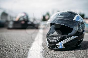 Racer helmet on asphalt, karting motor sport concept, go kart outdoor track, carting race