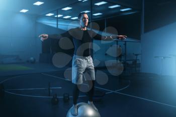 Strong man on training, balance workout with bouncy ball in gym. Active exercises in sport club
