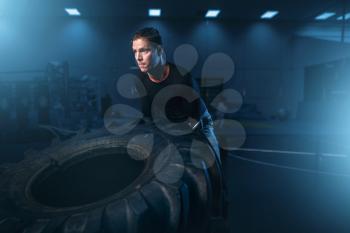 Male athlete on training, workout with heavy tire in gym. Energy exercises in sport club