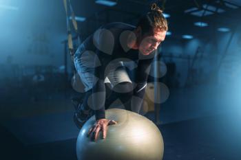Athletic man on training, balance workout with bouncy ball in gym. Active exercises in sport club