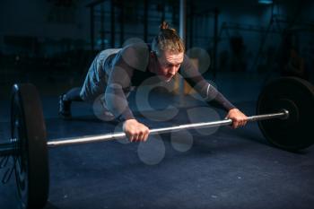 Strength athlete on training, pushups with barbell in gym. Active  exercises in sport club