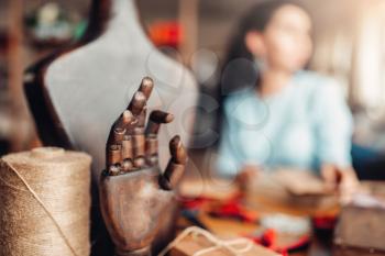 Needlework tools and accessories, wooden hand and mannequin, closeup, female craftman on background. Handmade jewelry, workshop interior