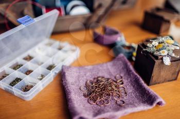 Metal rings, equipment for needlework, bracelets on wooden table, closeup. Handmade jewelry. Handicraft, bijouterie making