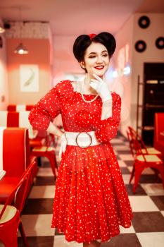 Pin up woman in red dress with white dots, vintage style. Retro cafe interior with checkerboard floor