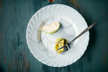 Plate with a slice of apple and measuring tape closeup. Weight loss diet concept