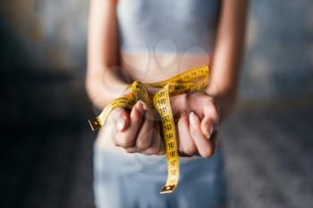 Skinny female hands are tied with measuring tape. Fat or calories burning concept. Weight loss