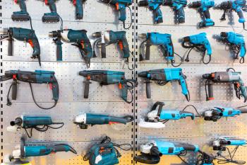 Hand-held power tools on stand in store. Hammer drills, grinding machines, electrical screwdrivers, workshop tools
