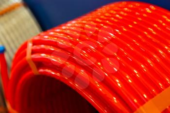 Roll of of red plastic pipe in plumbing shop, pvc. Coil of new water pipeline