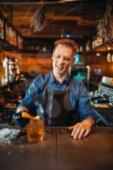 Male bartender in apron works at the bar counter. Alcohol beverage preparation. Barman occupation, barkeeper job