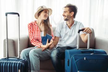 Young couple with suitcases sitting on the couch. Fees on journey concept. Luggage preparation. Travelling or tourism