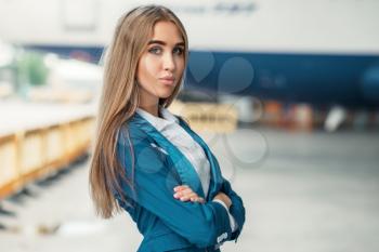 Attractive stewardess in uniform poses against airport building. Air hostess in suit near terminal. Flight attendant occupation