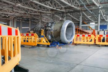 Plane engine without covers on maintenance in hangar, nobody. Jet airplane turbine on the cart after repairing. Air transportation safety concept