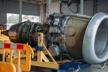 Jet airplane turbine on repairing in hangar, plane engine without covers on maintenance, nobody. Air transportation safety concept