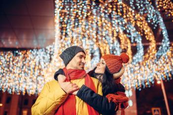 Winter evening, smiling love couple hugs on the street. Man and woman having romantic meeting, happy relationship