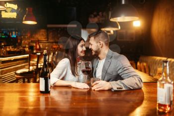 Romantic evening in bar, love couple kissing at wooden counter. Lovers leisures in pub, husband and wife relaxing together in nightclub