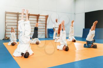 Children karate, kids in kimono practice martial art in hall. Little boys and girls in uniform on sport training, upside down exercise