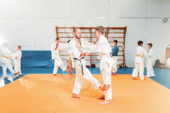 Boys in kimono practice martial art in sport gym. Kid judo, young fighters on training in hall. 