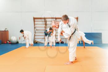 Kid judo, young fighters on training in hall. Little boys in kimono practice martial art