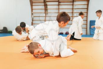 Little boys in uniform practice kid judo. Young fighters on training in gym, martial art for defense