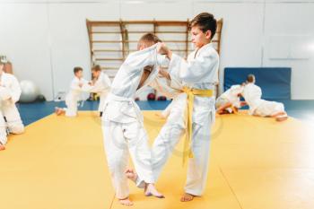 Boys in kimono fights, kid judo training. Young fighters in gym, martial art for defense
