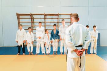 Trainer and childrens in kimono, kid judo training. Young fighters in gym, martial art for defense