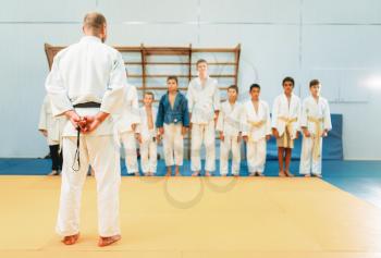 Trainer and little boys in kimono, kid judo training. Young fighters in gym, martial art for defense