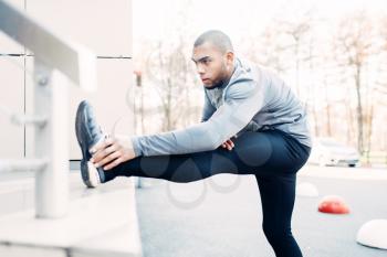 Male athlete doing stretching exercise before run. Jogger on morning fitness workout. Runner in sportswear on training outdoor