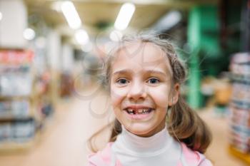 Smiling little girl without tooth, childrens happiness in pet shop. Kid customer in petshop